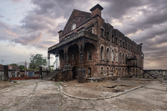 View of the historic Old Fourah Bay College building featuring its red brick facade and ornate arched windows under a cloudy sky in Freetown, Western Area, Sierra Leone.