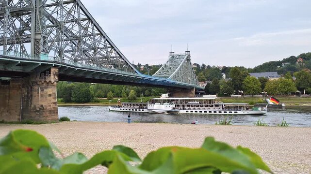 Blue Wonder Elbe bridge in Dresden with riverbank and a passing tour boat on a sunny day in summer