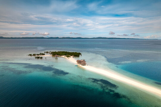 Aerial view of a pristine sandbar stretching into the azure sea, contrasting with the lush island vegetation, Buntod Reef, Mobo, Bicol, Philippines.