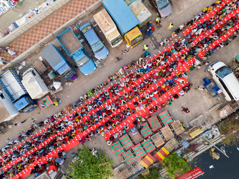 Dhaka, Bangladesh - 17 March 2026: Aerial view of vibrant red carpets laid out for prayer amidst the urban landscape, contrasting sharply with the parked vehicles and surrounding buildings.