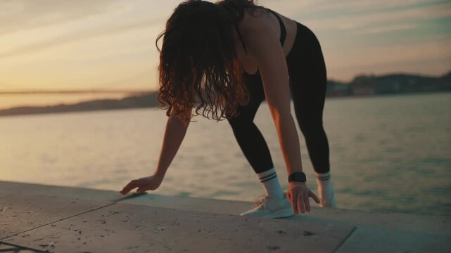 Fit woman doing push-ups workout at sunrise by the river