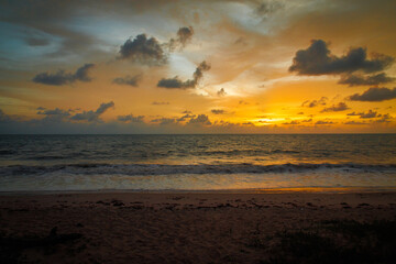 Obraz premium Golden ocean sunset with soft waves and cloudy sky