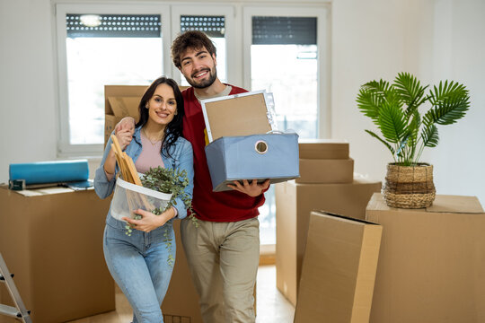 Portrait of a happy young couple smiling at the camera while moving into a new apartment.
