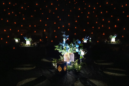 View of a formal outdoor dinner table setting with a glowing lantern centerpiece and green foliage against a backdrop of many small lanterns Namibia.