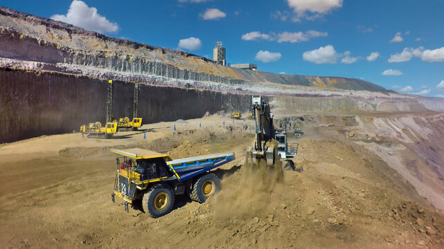 Heavy Machinery Operating in a Large diamond Open Pit Mine under a blue sky.