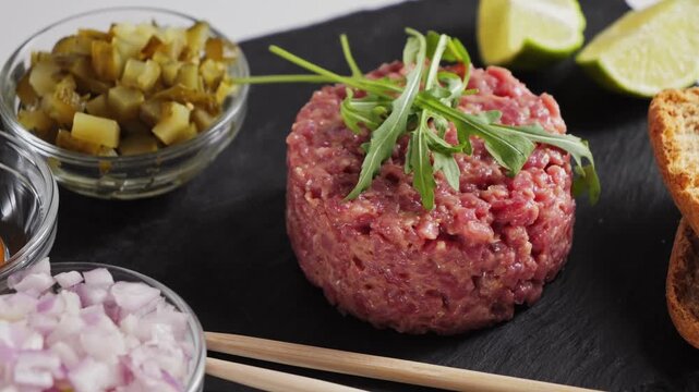 Beef tartare with egg yolk, capers, onions and bread slices. A gourmet dinner. High quality 4k footage