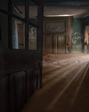 View of the interior of an abandoned house filled with sand dunes and light rays in Kolmanskop, Karas Region, Namibia.