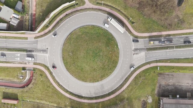 Genk, Belgium. Top-down drone hoovering over busy roundabout with flowing traffic and transport vehicles