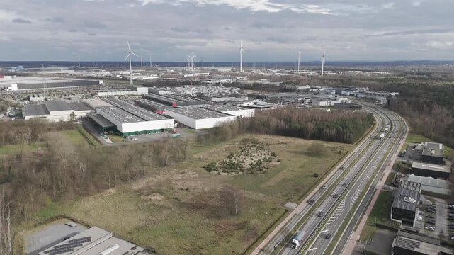 Genk, Belgium. Aerial drone glide over industrial zone with highway traffic and wind turbines