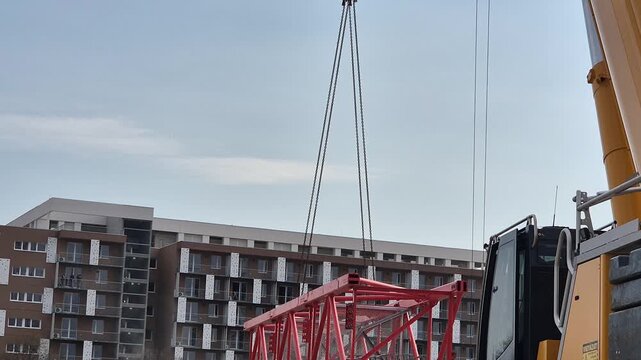 Slow motion rear shot of a mobile crane beginning to lift a heavy tower crane segment, highlighting the steady power and mechanical tension.