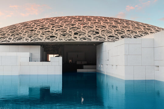 6 December 2025, Abu Dhabi, UAE: Louvre dome building reflecting in the calm museum water feature. Iconic architecture creating light patterns