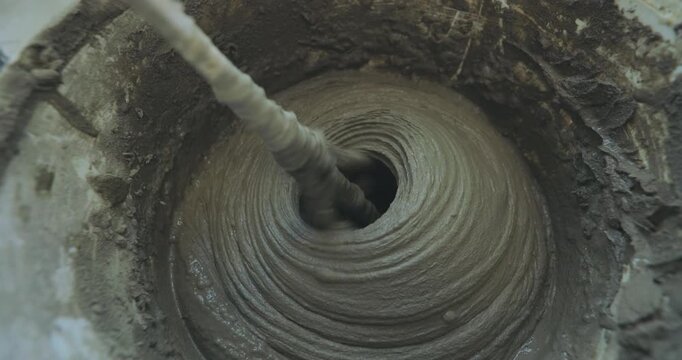 A man kneads tile mortar in a bucket with a paddle mixing drill. Mixing tile mortar for laying ceramic tiles or porcelain tiles. Close-up