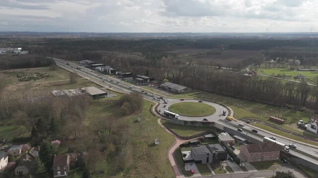Genk, Belgium. Aerial drone footage of busy roundabout with trucks and suburban-industrial surroundings