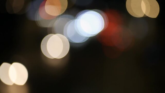 A short nighttime clip showing a city street with blurred light traffic, illuminated by streetlights, capturing a simple moment of everyday urban life.