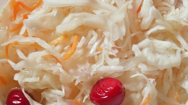 Rotating close up of sauerkraut salad with carrot strips and cranberries showing texture of fermented homemade vegetables.