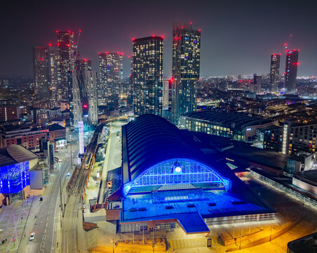 Manchester Central convention centre cityscape at night, illuminated skyline, tram lines and transport, aerial urban view, UK landmark, vibrant city lights and modern architecture