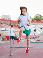 Fototapeta premium Children running on track at the stadium, practice during sports class in school training with their coach teacher, little fit boys and girls in sportswear training as athletes outdoor. Concept of sp