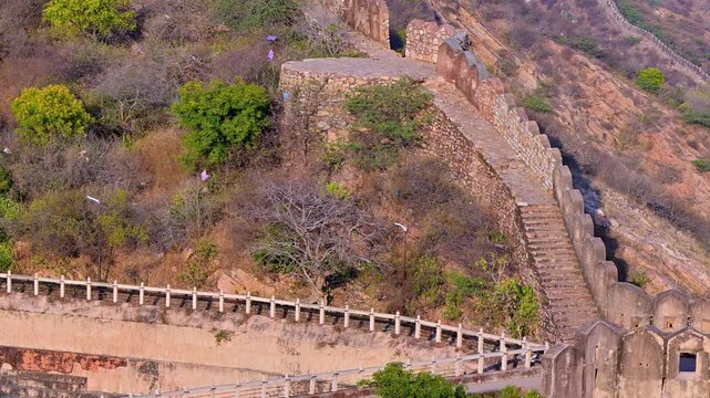 Daytime close view of Nahargarh Fort wall Jaipur showing stone fortification with stairway, watch platform, wall across hills, rocky terrain and historic architecture.