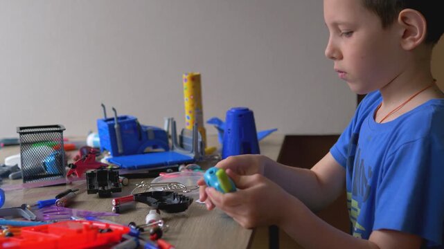 Boy Disassembling Electronic Toy at Desk, Junior Engineer Examining Small Speaker Component, Hands-on STEM Learning and Technical Curiosity