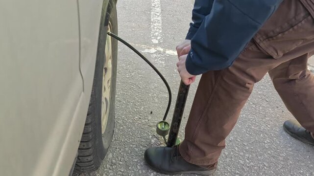 How to inflate a car tire using a hand pump in a parking lot