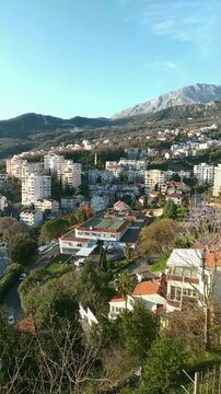 Layered development in Herceg Novi with residential buildings against the slopes of Orjen. Depicts urban expansion pattern, spatial adaptation, and interaction between city growth and rugged terrain.