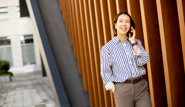 Korean woman talking on phone in urban area with wooden wall background