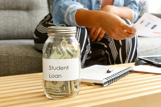 Student Loan Debt Concept with Money in Glass Jar and Study Materials