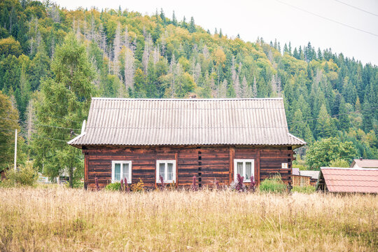 Old wooden house with white windows in a mountain Carpathian village
