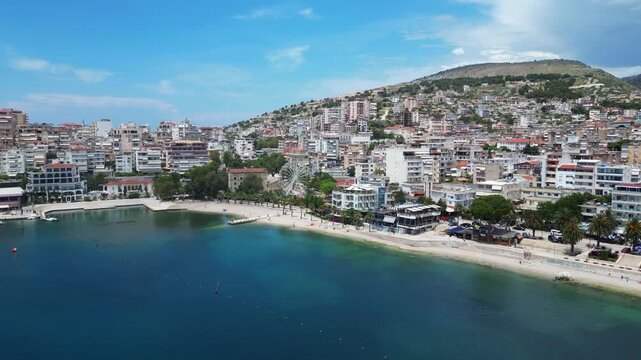 Saranda Waterfront Aerial 4K Drone Shot &ndash; Palm Lined Promenade, Urban Beach, Ferris Wheel, Harbor with Ferry, cityscape, Albania Travel Destination