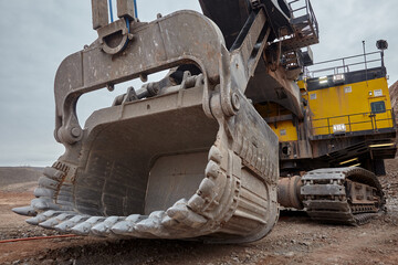 the colossal dipper of an electric rope shovel looms against a steel-grey sky, its serrated teeth and battle-worn steel shell radiating the unstoppable force of modern large-scale mining.  © Beto Santillan