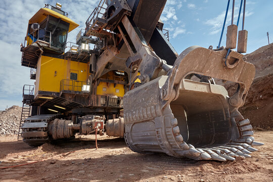 the colossal dipper of an electric rope shovel looms against a steel-grey sky, its serrated teeth and battle-worn steel shell radiating the unstoppable force of modern large-scale mining. 