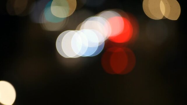 A short nighttime clip showing a city street with blurred light traffic, illuminated by streetlights, capturing a simple moment of everyday urban life.