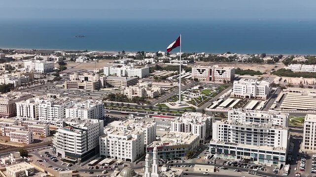 Muscat, Oman. Aerial drone view of the capital of Oman against the backdrop of the Gulf of Oman. Flight over the government district with many ministries and a huge Omani flag pole.