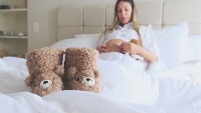 Expectant mother holding headphones on her belly while resting in bed