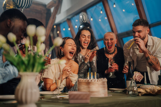 Diverse friends celebrating birthday party, enjoying cake and blowing candles, feeling joy and happiness