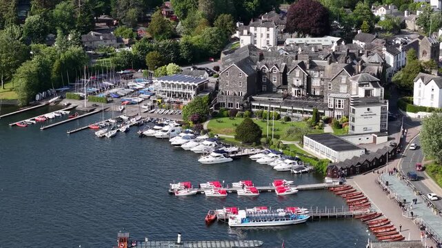 Scenic view of boats and buildings along the waterfront in Ambleside, England during a sunny day