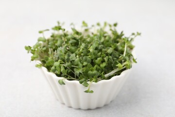 Fototapeta premium Fresh microgreens in bowl on white table, closeup