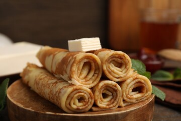 Tasty rolled crepes with butter and mint leaves served on wooden table, closeup © New Africa
