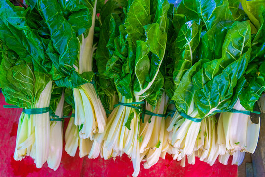 Fresh chard bundles arranged neatly on display in a market setting in France during the daytime