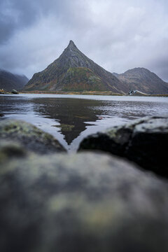 Volanstinden mountain peak shows reflection in a fjord at Fredvang in Lofoten Islands, Norway during cloudy weather
