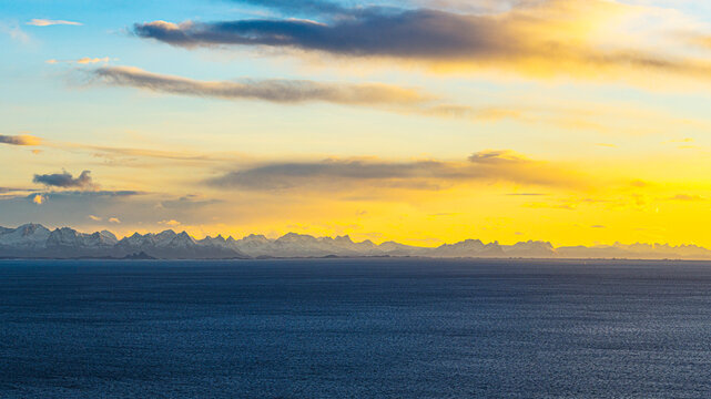 Sunset view over the blue water of the Norwegian Sea in Henningsvaer, Lofoten Islands during evening hours in Nordland, Norway