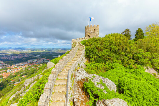 Explore the winding path leading to the tower of Castelo dos Mouros in Sintra, Portugal with views of the city and landscape