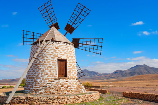 Windmill structure on Fuerteventura in the Canary Islands with blue sky and mountains in the background
