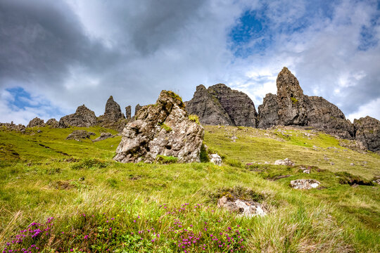 Old Man of Storr rises above green hills under cloudy sky on Isle of Skye in Scotland