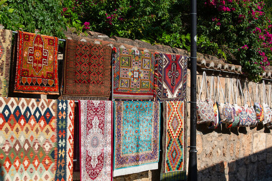 Carpets for sale displayed on a wall in Kaleici, Antalya, showing designs and colors from local artisans in Turkey