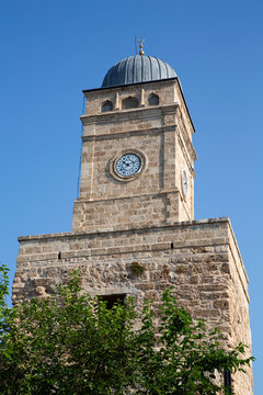 Historic clock tower stands tall under blue sky in Antalya, showcasing architecture from 1901 in Turkey