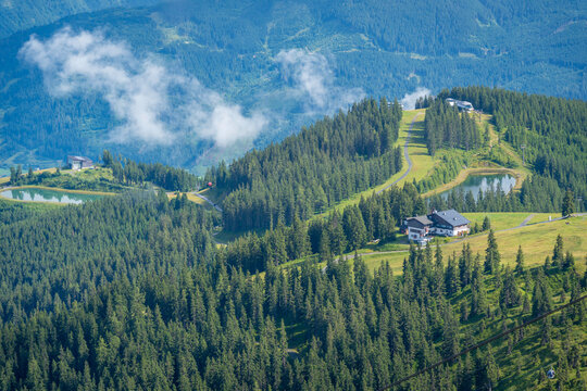 View from Schmittenhohebahn top station shows pine trees and clouds on sunny day in Zell am See, Salzburg, Austria