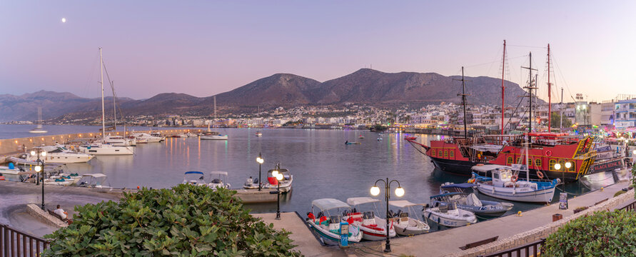 Boats in Port of Limenas Chersonisou at dusk with hills in the background in Crete, Greece