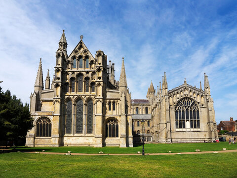 Ely Cathedral stands tall in Ely Cambridgeshire with its intricate architecture and surrounding green space under a clear blue sky