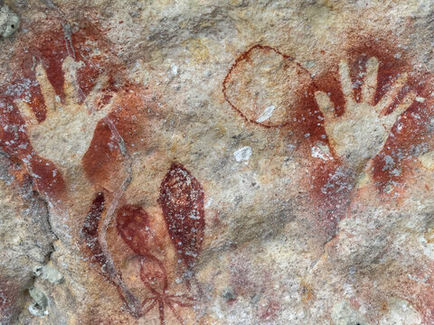 Ancient rock art depicts handprints and symbols on limestone cliffs in Berau Bay, Papua